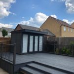 Composite Garden Building On A Raised Decking With A Matching Burnt Wood Grey Effect